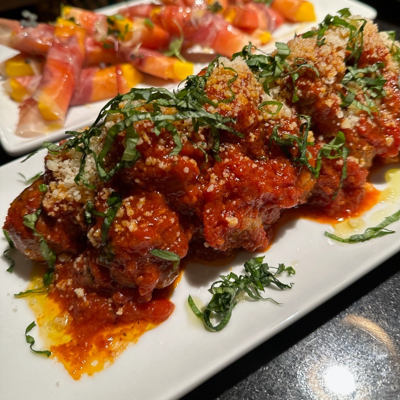 Meatballs in tomato sauce topped with grated parmesan and ribbons of basil