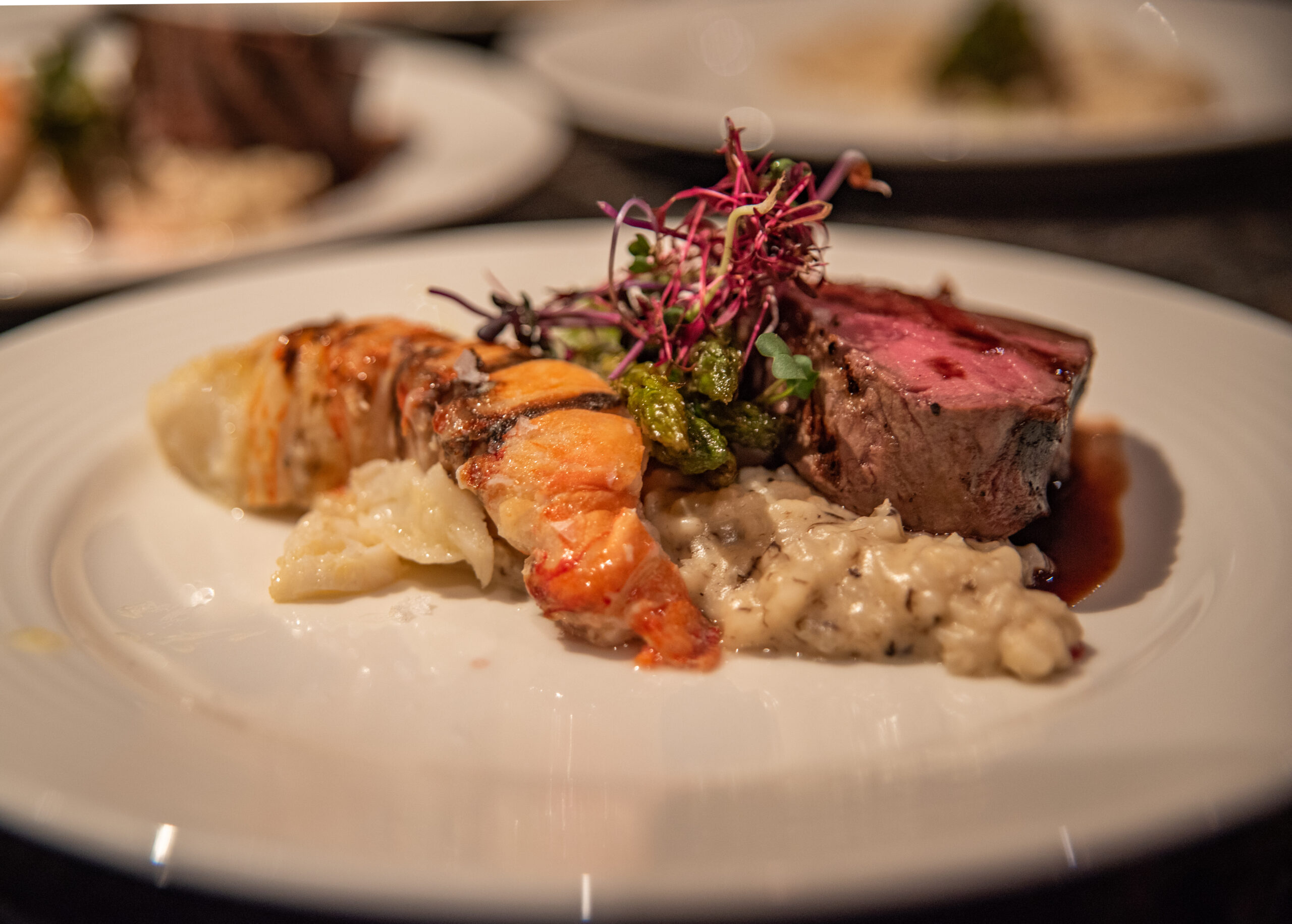 Filet mignon and Caribbean lobster tail over risotto, topped with microgreens